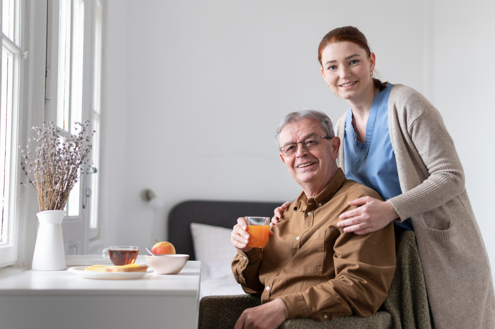 a female home health care caregiver assisting an elderly man with his meal