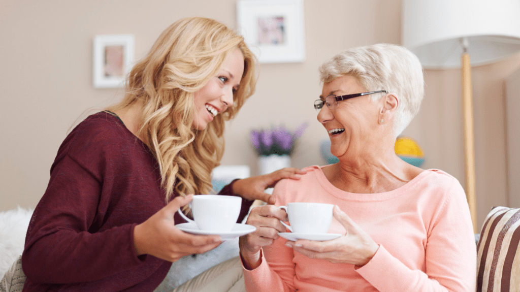 In home care vs nursing home. A grandmother and granddaughter laughing together at home.