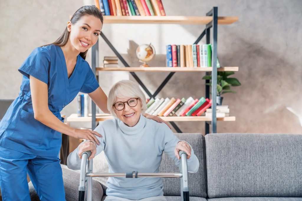 a caregiver helps a woman using a walker. smiling indoors. caucasian