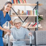 a caregiver helps a woman using a walker. smiling indoors. caucasian
